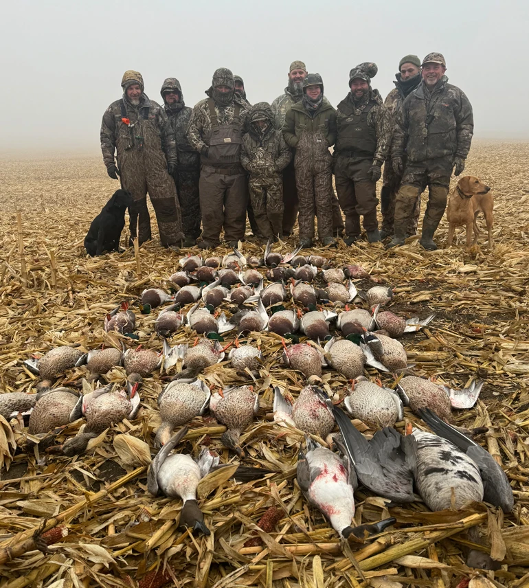 Group of hunters standing in a harvested field behind a spread of ducks during a foggy North Dakota waterfowl hunt